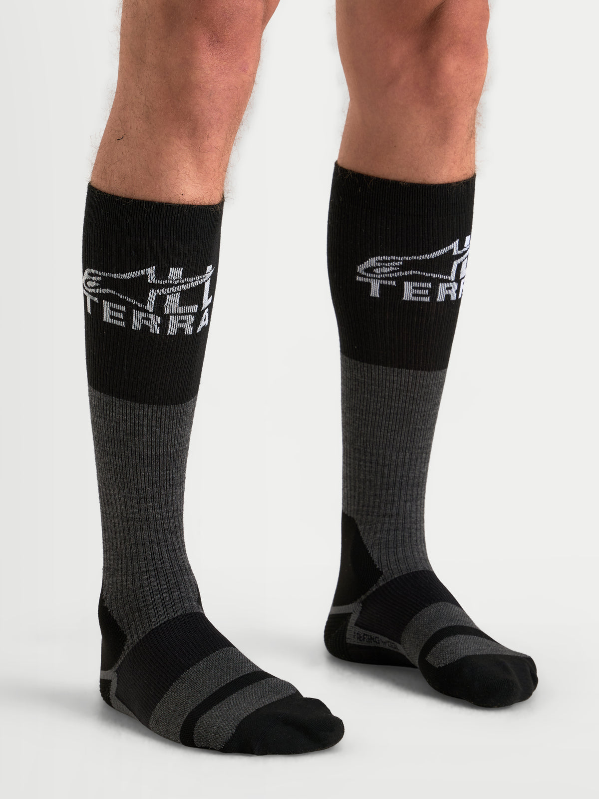 Alpinestars AT-8 Merino sokken, adventure-motorsokken over de kuit in grijs en zwart, met merinowolmix en All Terra branding, gedragen door model