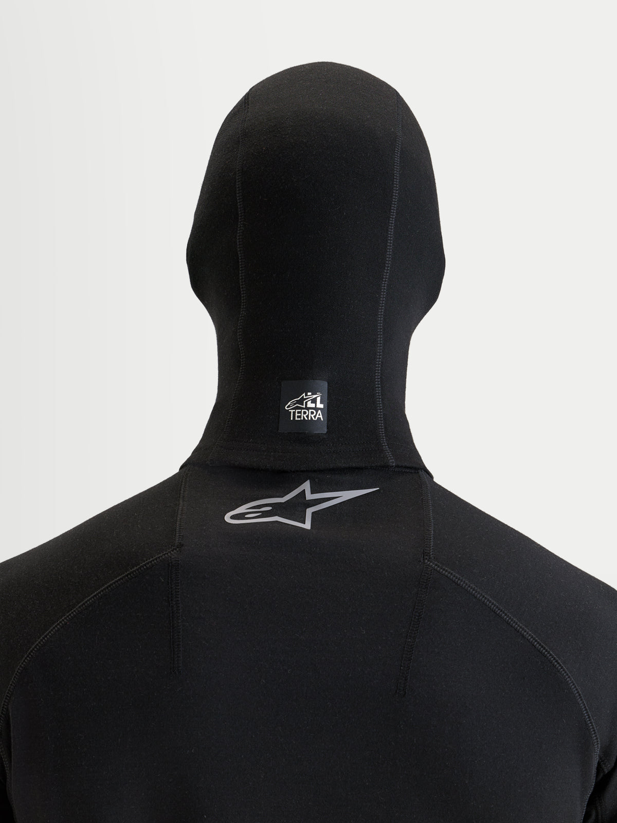 Alpinestars AT-8 Merino bivakmuts, zwarte motorbivakmuts, achteraanzicht met een All Terra label op de nek en een reflecterend Astar logo op de bovenste rug, thermische merinowol constructie voor koud weer