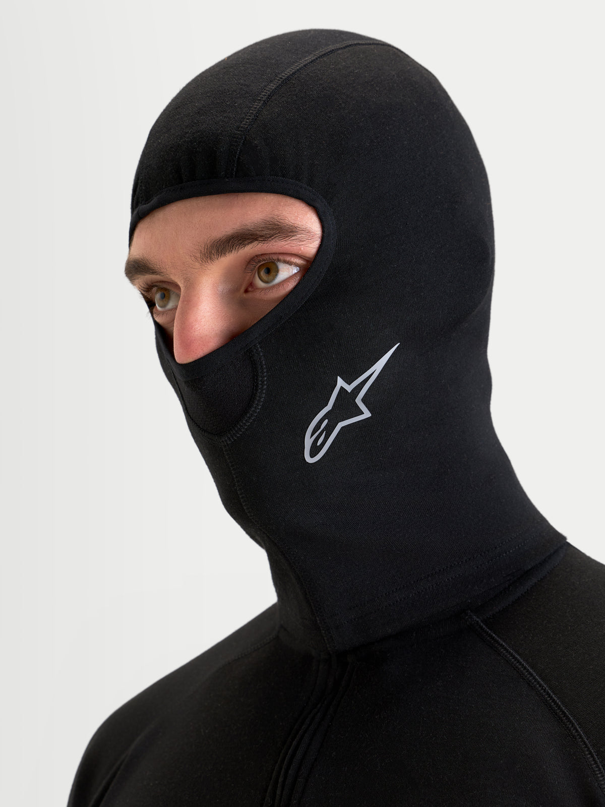 Alpinestars At 8 Merino bivakmuts, zwarte motor-bivakmuts gedragen door een model, met merinomix constructie, platte naden en een geprint Astar logo