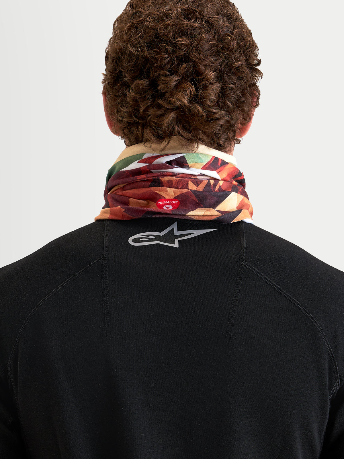 Alpinestars Buff Peaks PrimaLoft Neck Tube, earth brown and multi-color, rear view on a model showing insulated tubular knit construction with PrimaLoft branding and breathable performance gear
