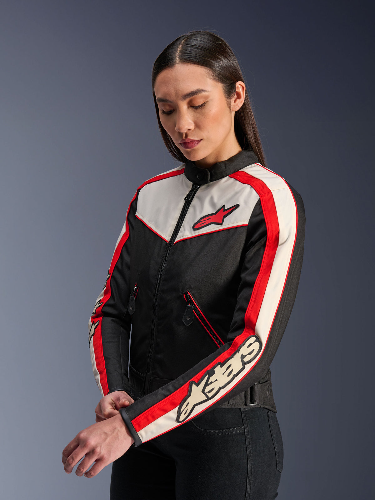 Veste Alpinestars Stella T-Dyno WR, veste de moto en textile pour femme, noir, écru et rouge vif, design d'inspiration vintage avec logo Alpinestars rouge sur la poitrine et marquage sur la manche, portée par un mannequin en studio