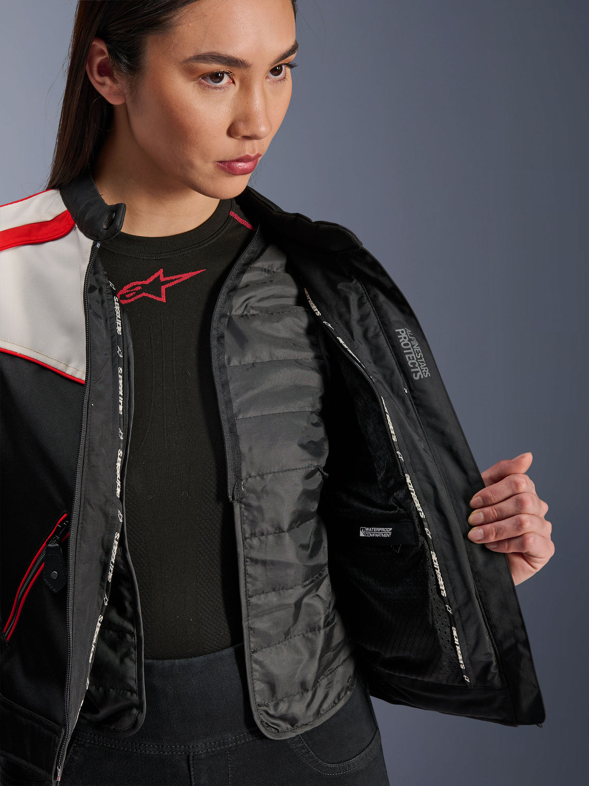 Veste Alpinestars Stella T-Dyno WR, veste moto pour femme, noir, écru et rouge vif, vue intérieure rapprochée montrant le gilet thermique matelassé amovible, le compartiment intérieur imperméable et le logo « ALPINESTARS PROTECTS ».