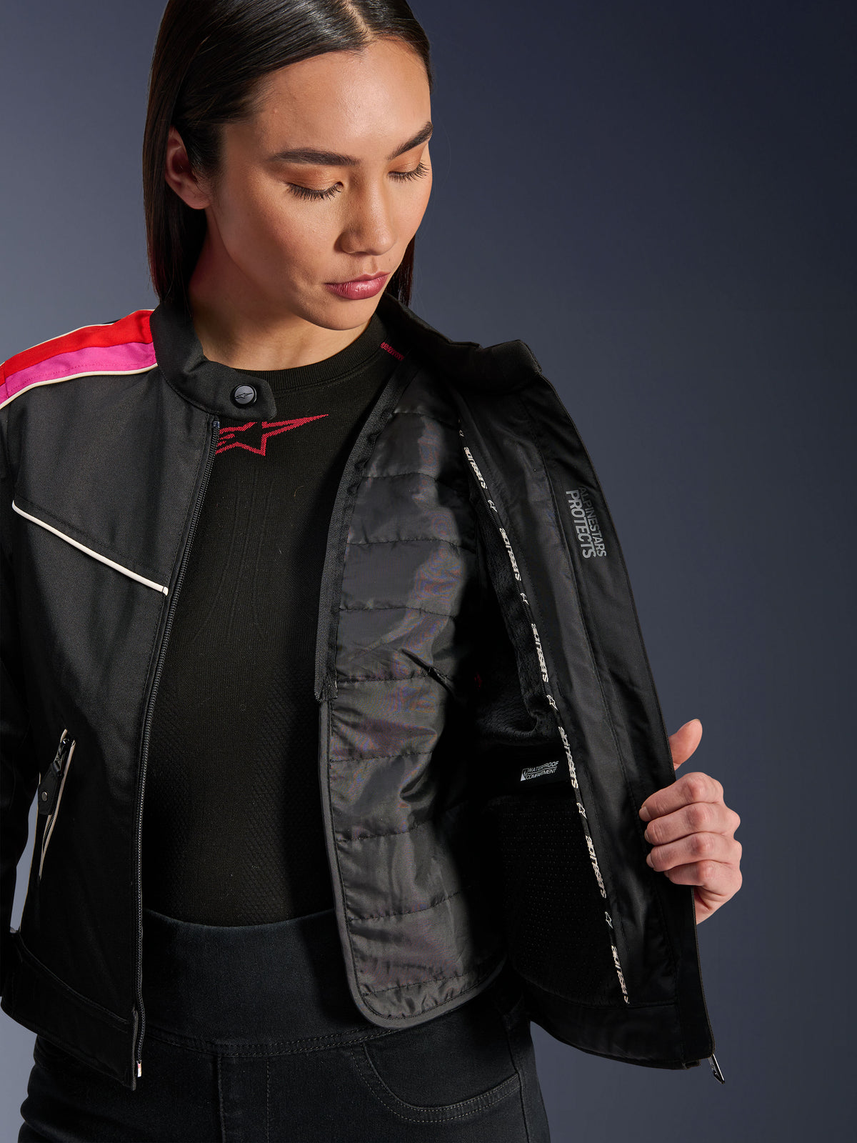 Alpinestars Stella T-Dyno WR Jacket, Black Bright Red Fuchsia textiele motorjas, opengeritst om het interne gewatteerde thermische vest en de waterdichte zak te tonen, vintage-geïnspireerde bikerpasvorm voor dames