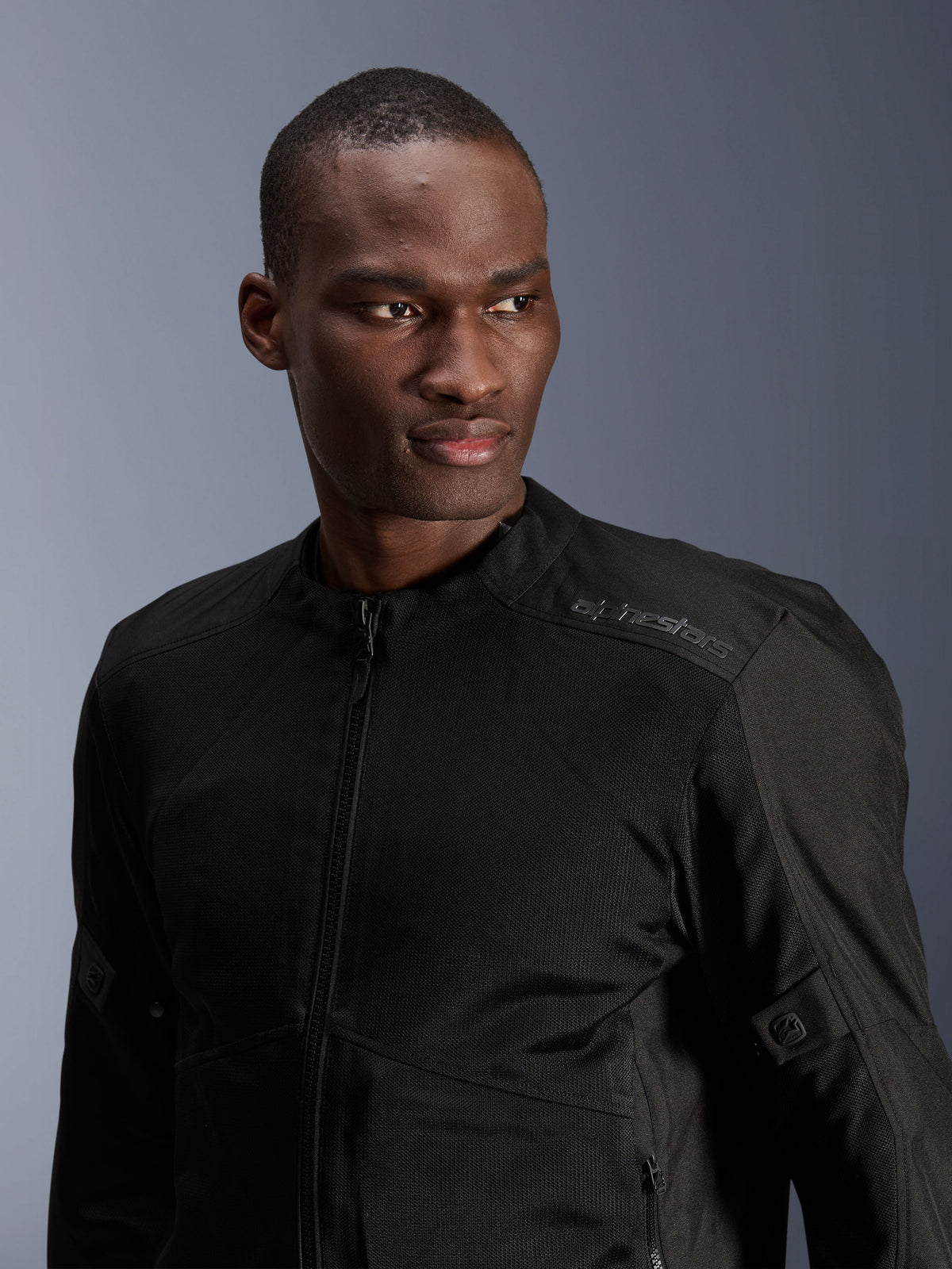 Alpinestars C-1 Air Jacket, Black, urban motorcycle jacket with tech mesh panels, worn by a model, featuring subtle heat-transfer Alpinestars logo on the shoulder, designed for airflow and lightweight comfort in warm weather
