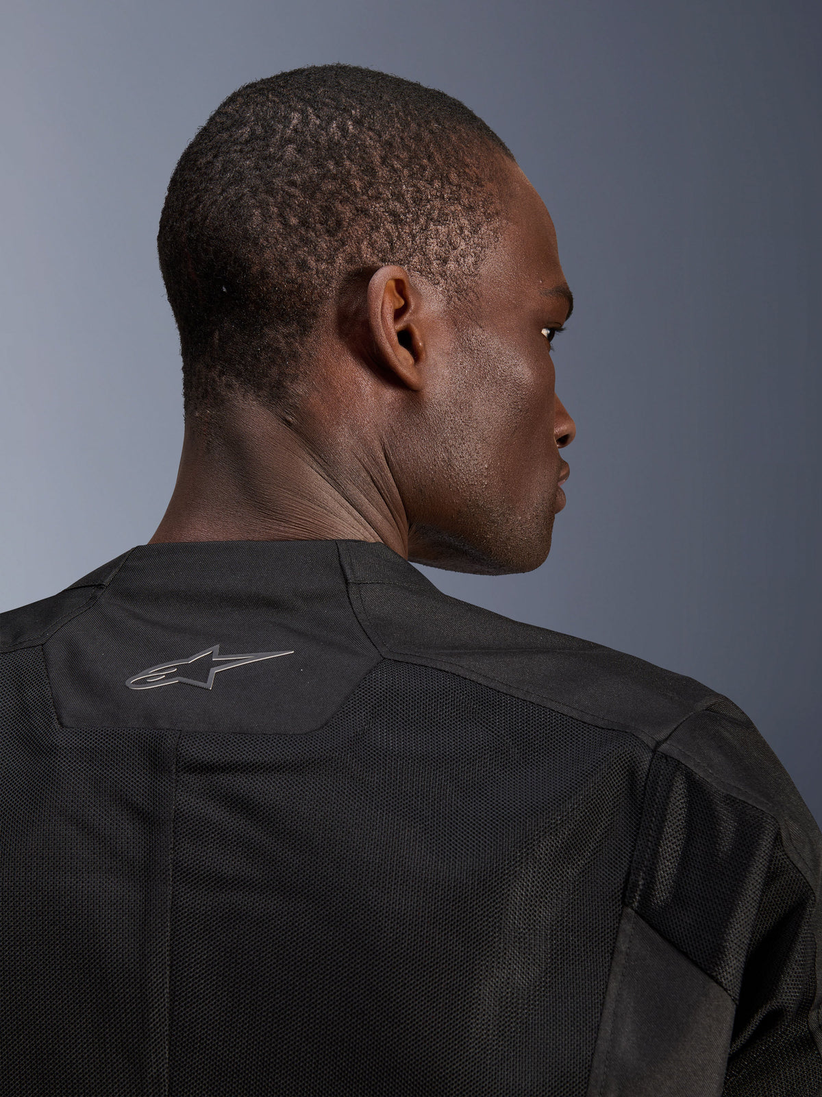 Alpinestars C-1 Air Jacket, Black Motorcycle Jacket, close-up of the back showing breathable tech mesh panels and a reflective Alpinestars logo on the collar, urban riding gear