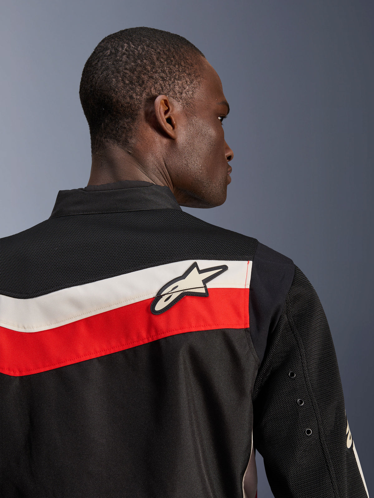 Alpinestars T-Dyno Air Jacke, Schwarz Hellrot Ecru, Nahaufnahme von oberem Rücken und Schulter, mit horizontalen roten und ecrufarbenen Streifen und einem weißen Astars-Logo, atmungsaktive 3D-Mesh-Einsätze an Passe und Ärmeln, moderne klassische Textil-Motorradjacke