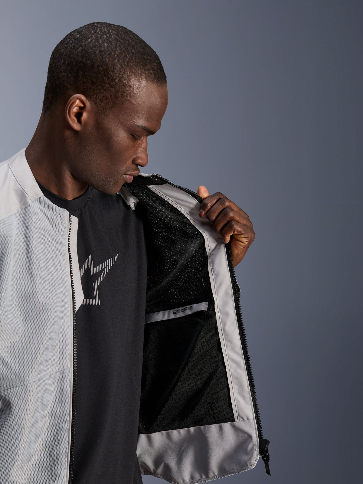 Male model wearing the Alpinestars C-1 Air Jacket in Silver, opening the front to reveal the black tech mesh interior lining and a zippered waterproof inner pocket.