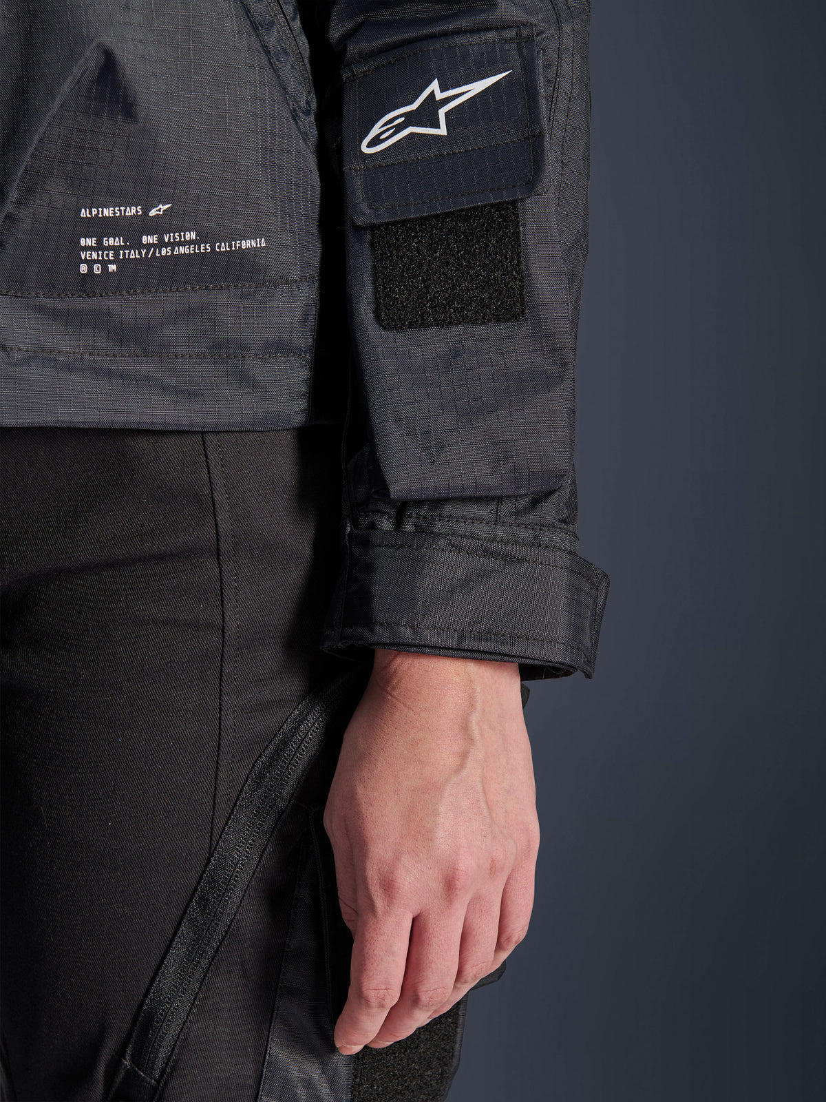 Alpinestars Molly Air Jacke, Detailansicht von schwarzem Ripstop-Textil, weißes Astar-Logo auf Ärmeltasche mit Klett-Patch, verstellbarer Ärmelbund und aufgedruckter Markenschriftzug an der Seite, urbane Motorradbekleidung für Damen