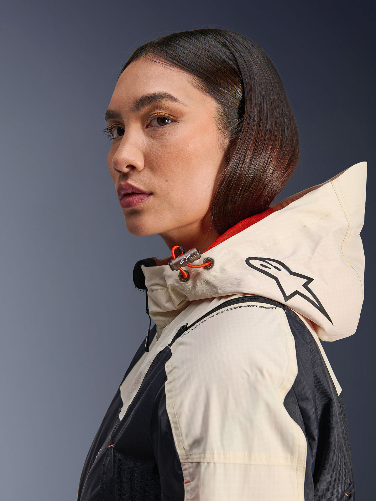 Alpinestars Molly Air Jacket, Black Almond, contemporary urban motorcycle jacket, side profile view of model wearing the hood with Alpinestars logo and orange drawcord accents, ripstop fabric texture