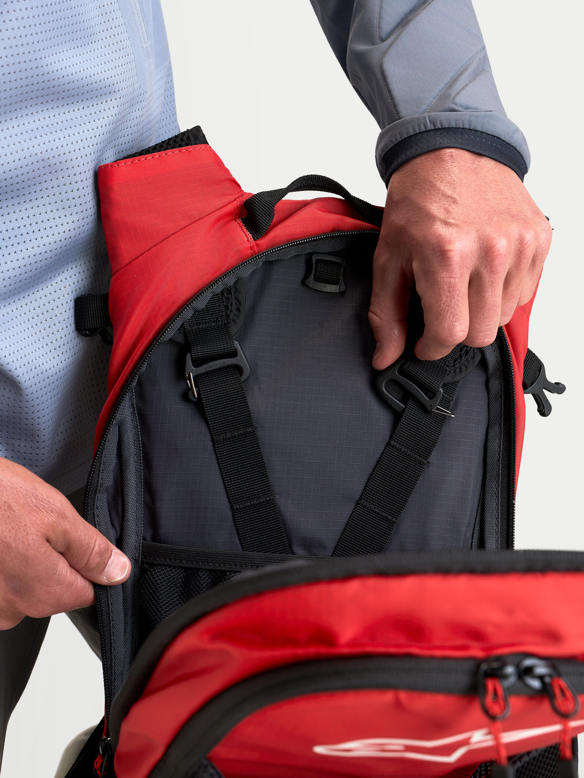 Alpinestars AT-9 Rucksack, Motocross-Rucksack in Schwarz und Leuchtrot, Nahaufnahme der Innenfächer und Gurteinstellungen