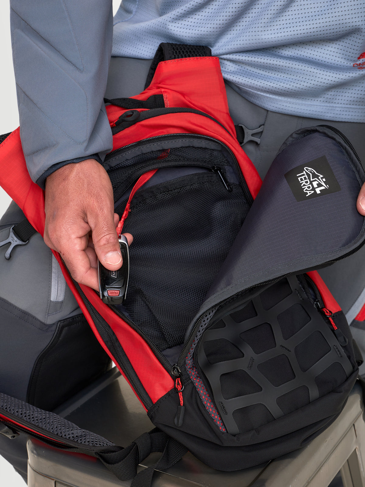 Alpinestars AT-9 Rucksack, Motocross-Rucksack in Rot und Schwarz, Nahaufnahme der organisierten Staufächer mit Reißverschluss, getragen von einem Model.
