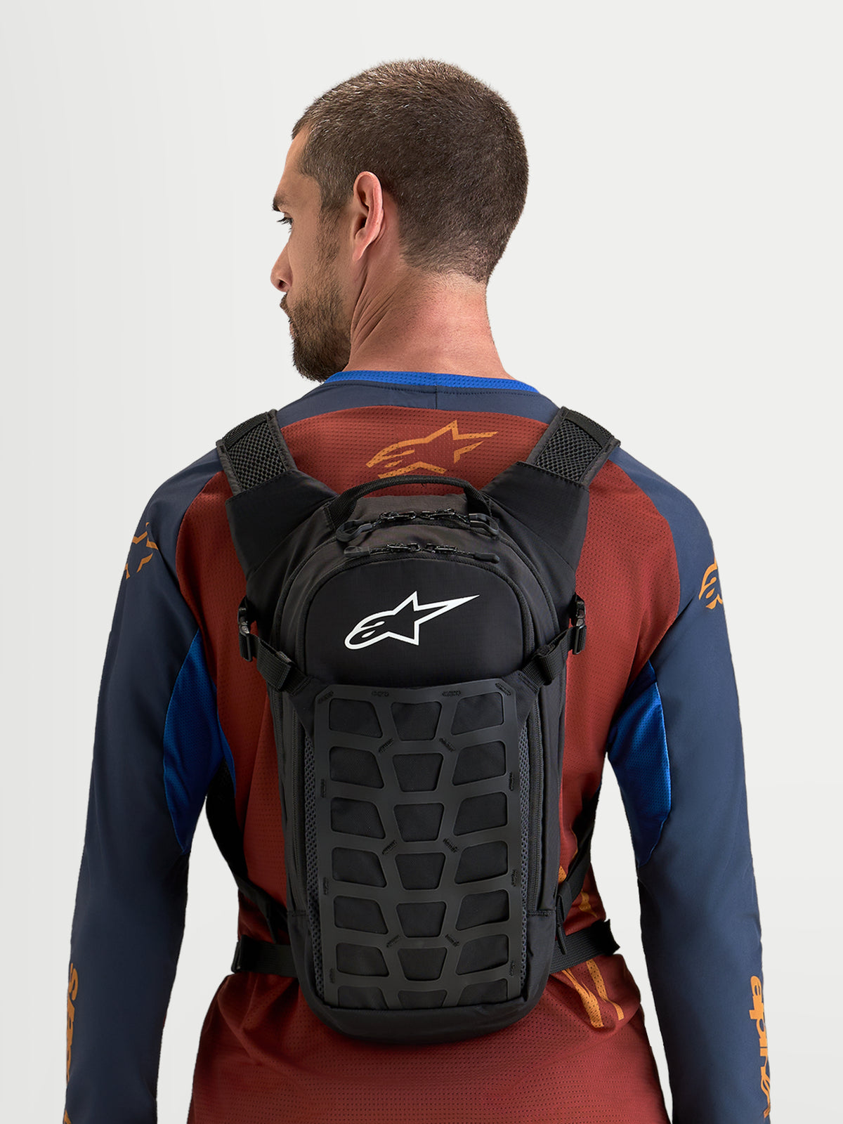 Alpinestars AT-9 Rucksack, Motocross-Rucksack in Schwarz mit weißem Alpinestars-Logo, kompaktes Design getragen von einem Model für Training und Alltag