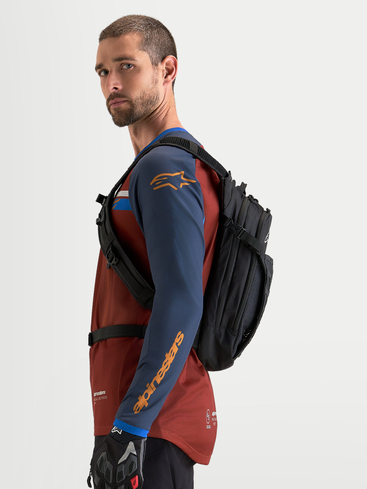 Alpinestars Sac À Dos AT-9, sac à dos de motocross et d'utilité quotidienne noir, vue de profil latéral porté par un modèle en équipement de pilotage