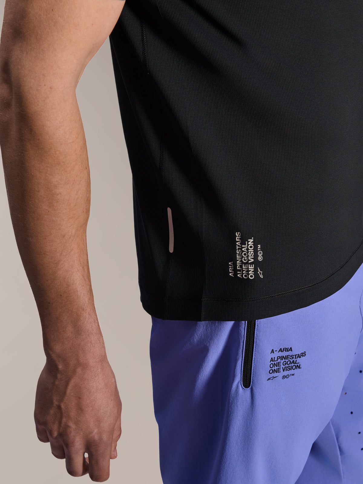 Short Alpinestars A-Aria Lite en coloris Baja Blue, short de VTT, avec marquage sérigraphié 'One Goal. One Vision.' et poche zippée, associé à un maillot A-Aria Switch noir, vue rapprochée d'un équipement technique de cyclisme.