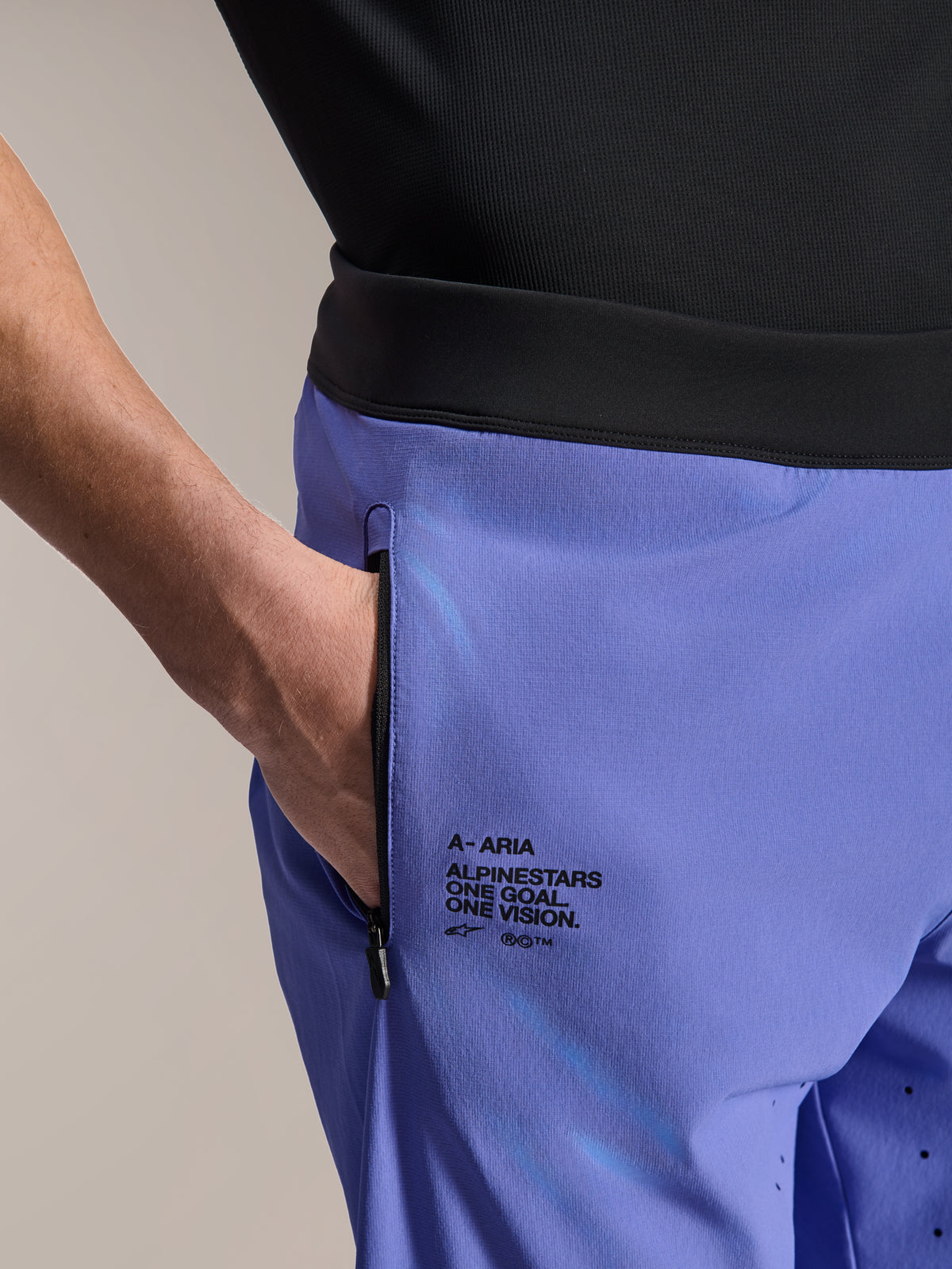 Alpinestars A-Aria Lite Short, short de VTT, Baja Blue, gros plan montrant la poche avant zippée et le marquage latéral avec le texte « One Goal. One Vision. », ceinture noire et tissu technique pour le vélo tout-terrain