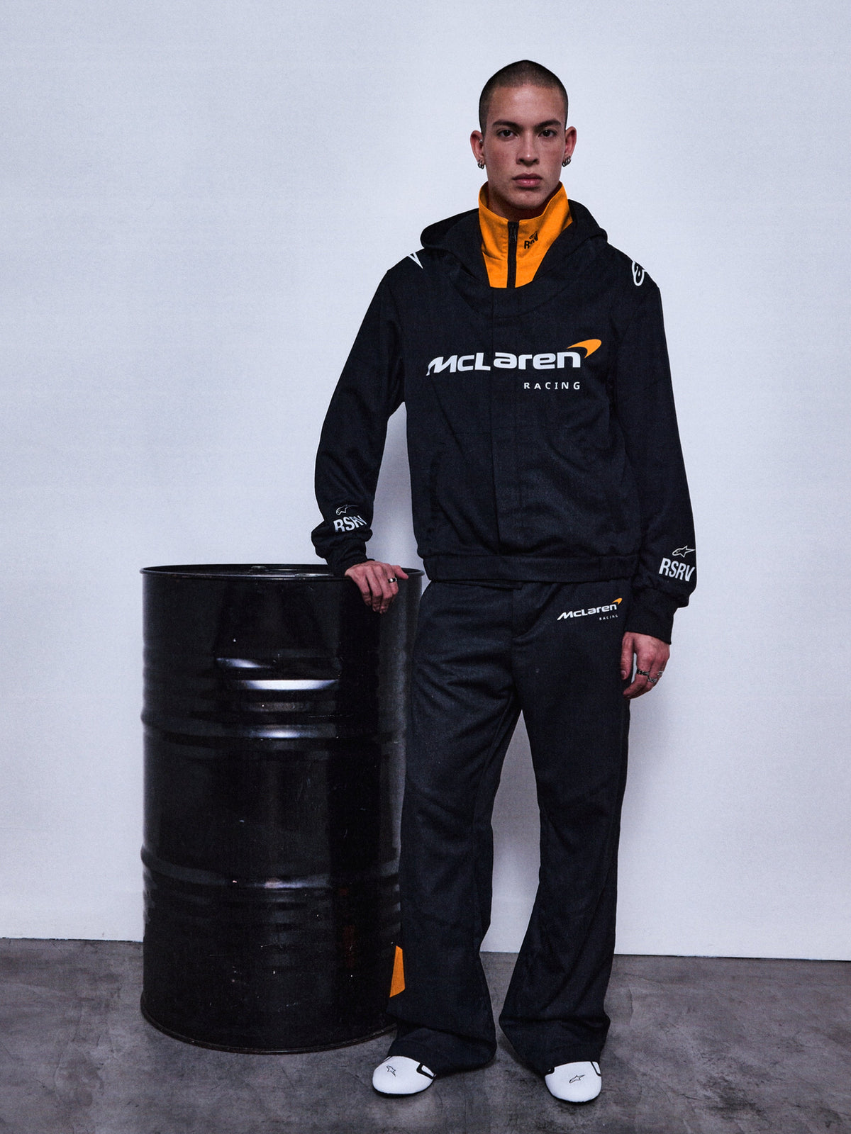Alpinestars RSRV Arena Suit Jacket, veste de survêtement McLaren Racing, noire avec doublure orange, logo McLaren Racing blanc, design lifestyle premium, portée avec pantalon assorti