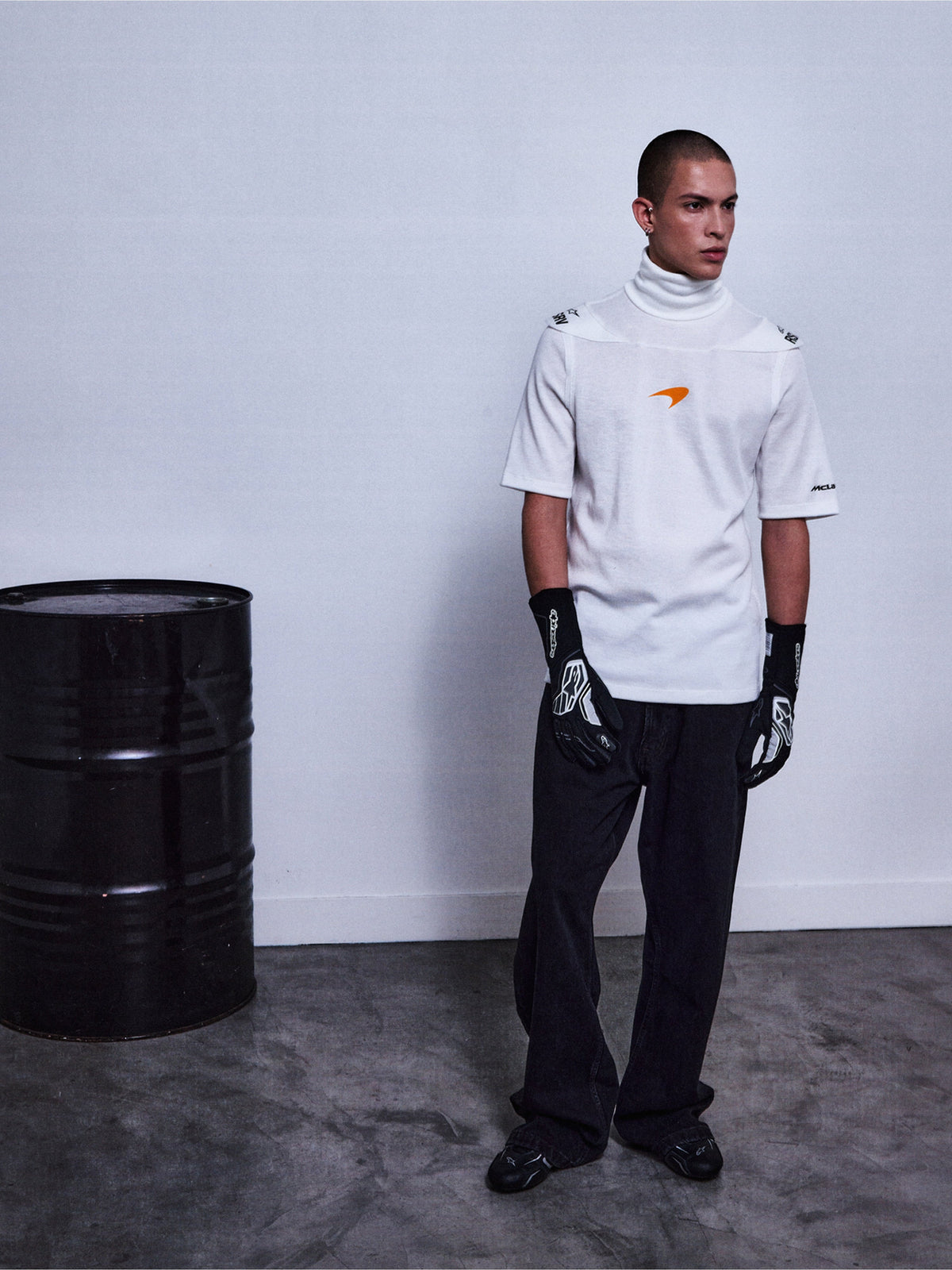 Alpinestars RSRV Pyro SS Tee, t-shirt blanc à col montant et manches courtes avec logo orange, porté avec gants noirs à motifs blancs, style streetwear premium