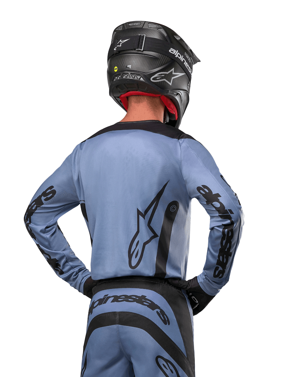 Maillot Alpinestars 2024 Fluid Lurv, maillot de motocross, bleu clair et noir, vue arrière du pilote montrant le grand logo étoilé et le marquage sur les manches, porté avec un casque noir et un pantalon tout-terrain assorti, équipement de course professionnel
