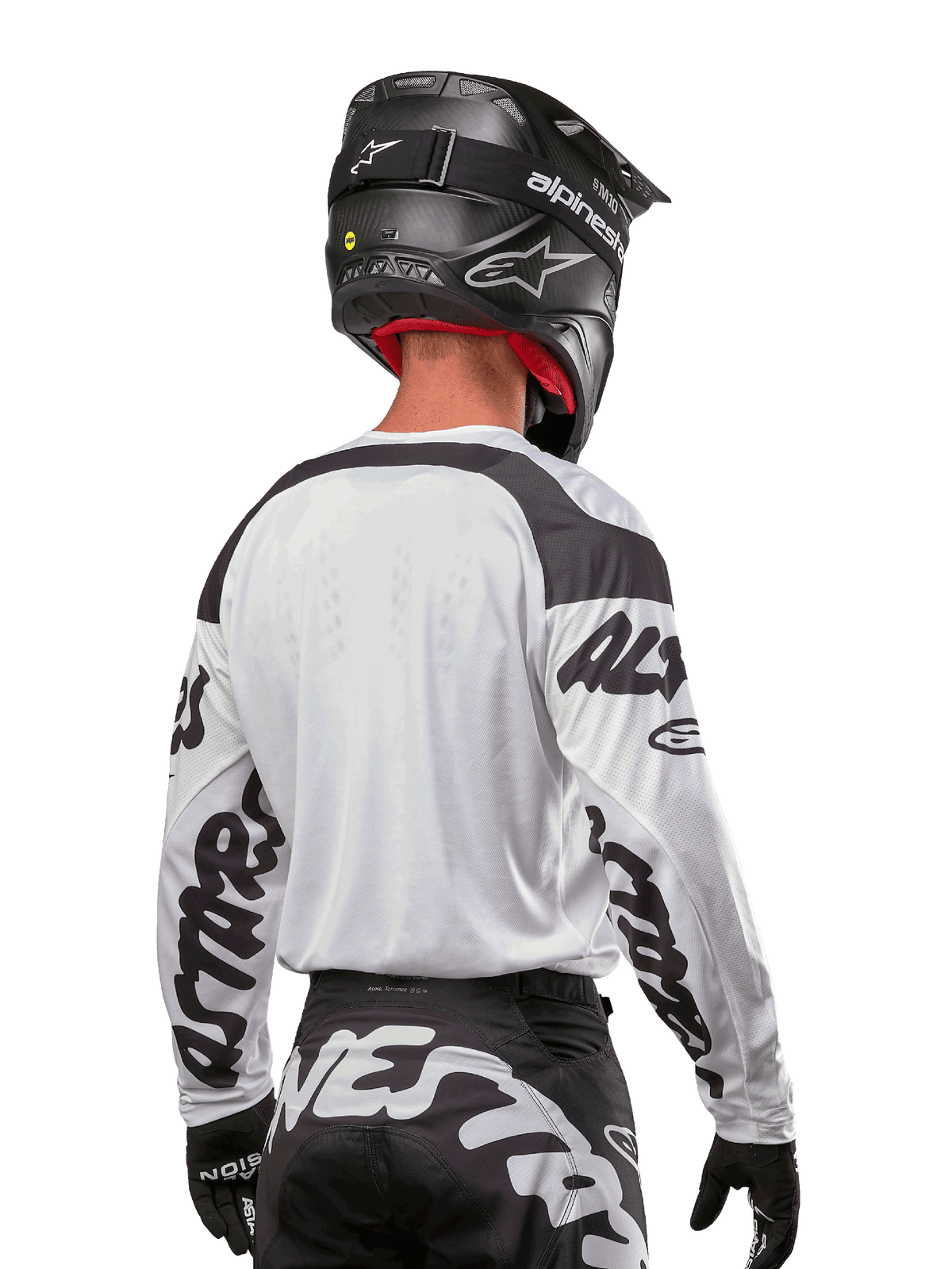 Maillot Alpinestars Racer Hana 2024, blanc et noir, vue de dos montrant la coupe ergonomique et le marquage imposant sur les manches, associé à un casque de motocross noir et un pantalon noir et blanc assorti, équipement de course haute performance pour la conduite tout-terrain