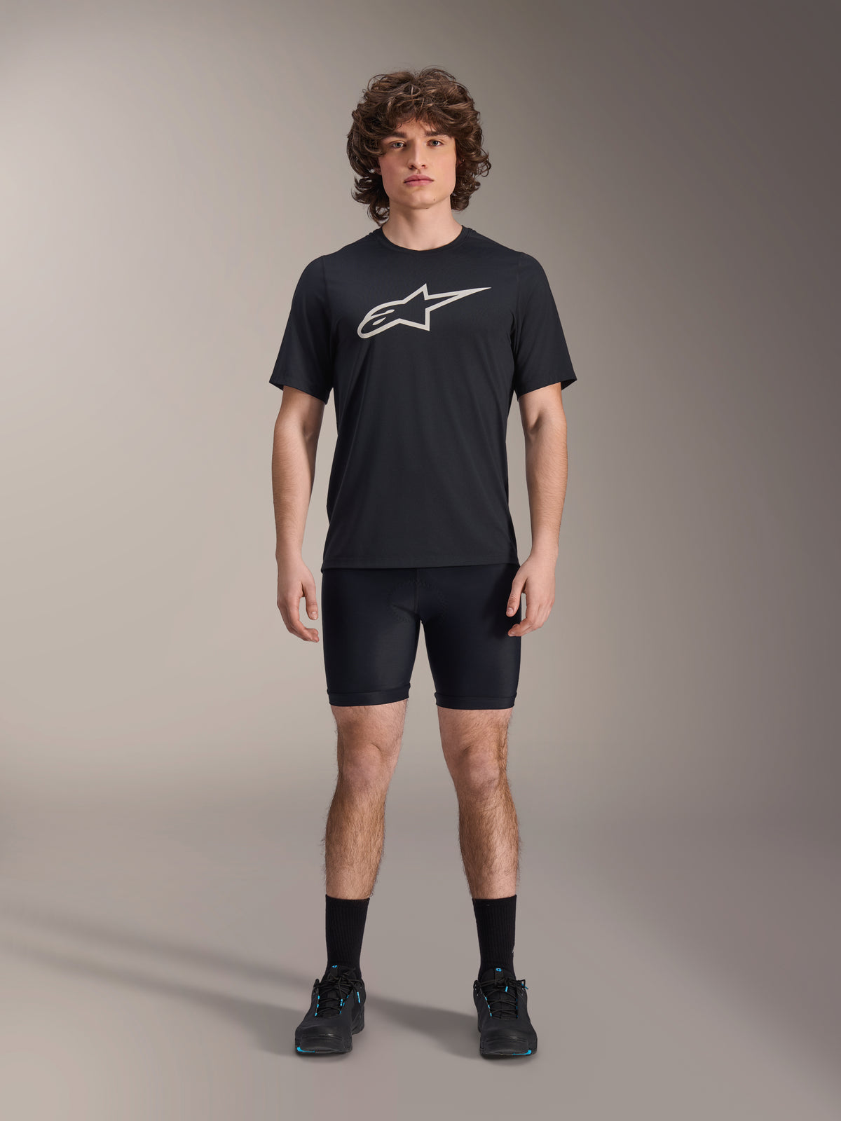 Alpinestars A-Dura Liner Shorts, zwarte fiets-binnenbroek, gedragen door een model met een zwart Alpinestars t-shirt met logo en zwarte fietsschoenen, nauwsluitend ontwerp voor MTB-prestaties en comfort in het zadel.