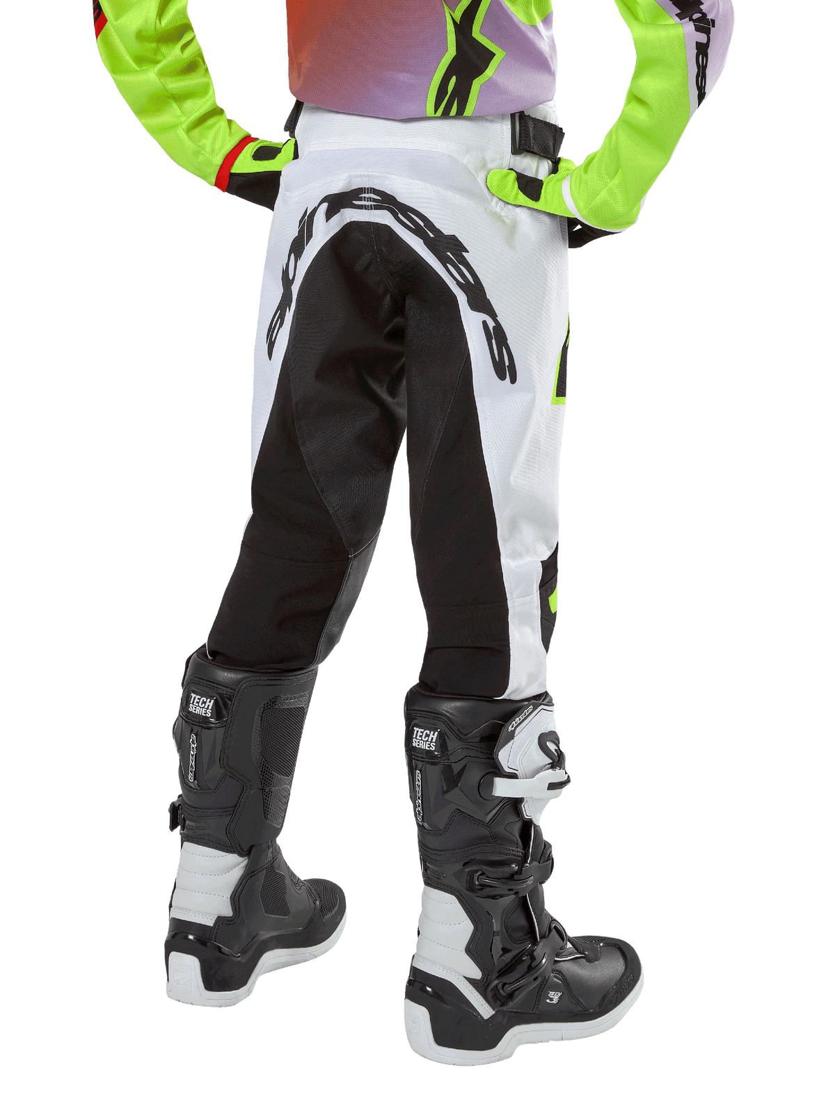 Alpinestars 2024 Youth Racer Lucent broek, motorcross broek, wit en zwart met neon accenten, achteraanzicht toont groot stretchpaneel aan de achterkant en Alpinestars-logo, gedragen met zwart-witte Alpinestars Tech Series laarzen