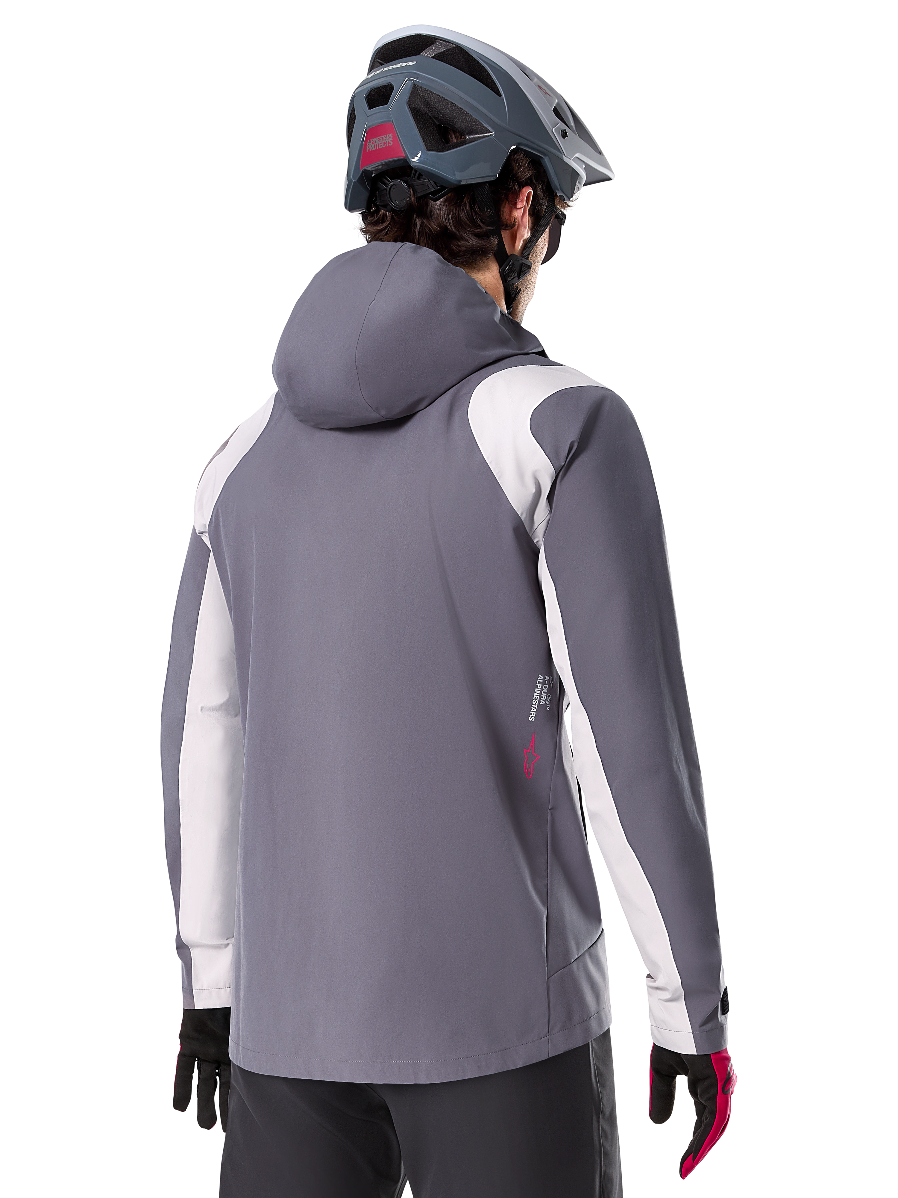 Veste de pluie Alpinestars A-Dura, veste de VTT, gris titane foncé, vue de dos avec empiècements gris clair sur les épaules et les bras, détail du logo rouge sur le côté, portée avec un casque de VTT gris et des gants noirs et rouges, vêtement technique de trail