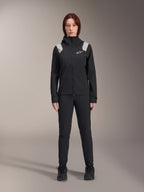 Veste de pluie Alpinestars Stella A-Dura, veste de pluie de VTT pour femme, noire avec empiècements gris clair aux épaules et logo blanc, portée avec un pantalon et des chaussures noirs assortis, dotée d'une capuche et de poignets réglables, conçue pour la pratique du VTT
