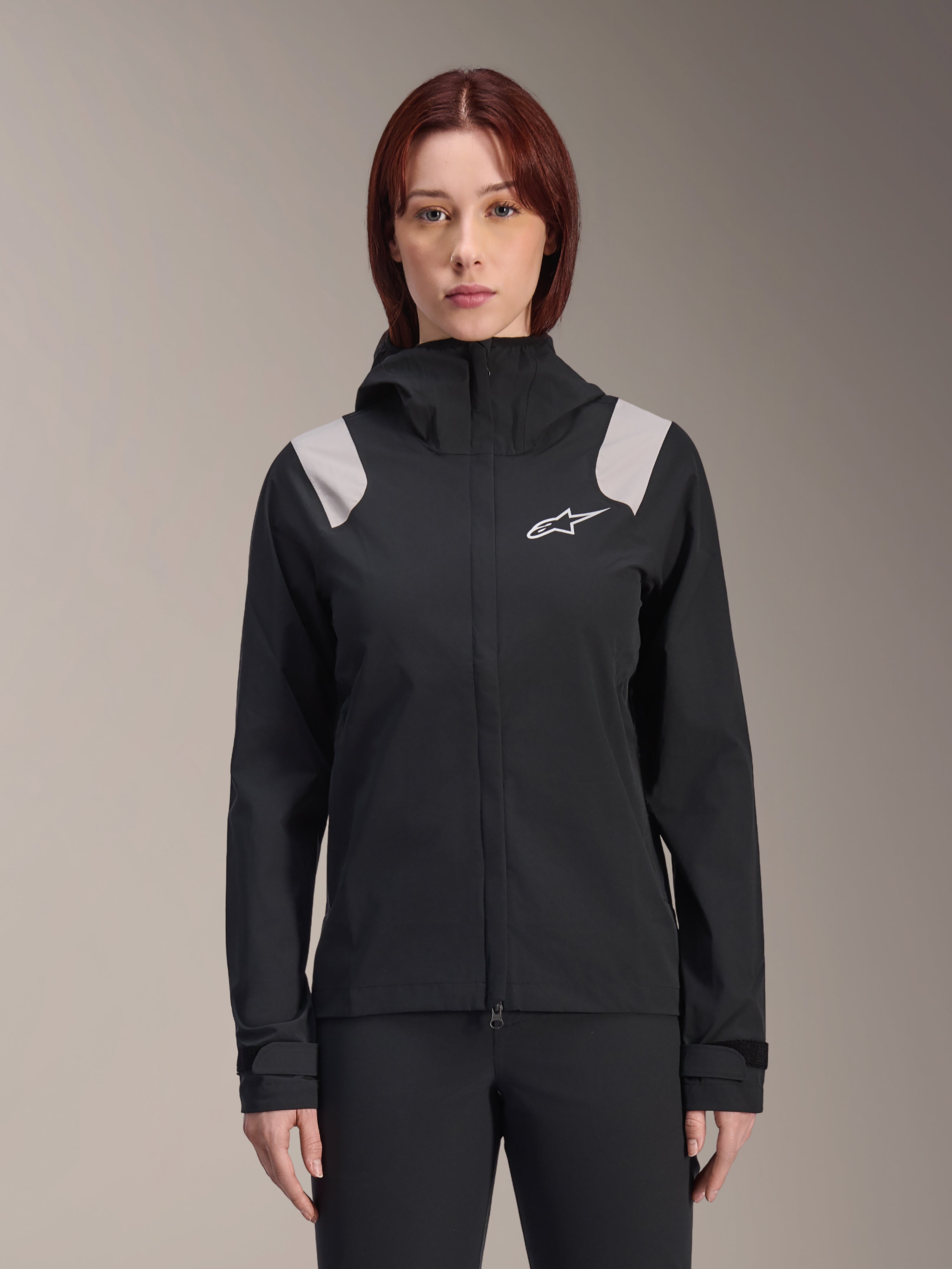 Alpinestars Stella A-Dura Regenjacke, Damen-Fahrrad-Regenjacke, Schwarz mit hellgrauen Schulterpartien, technische Shell-Jacke mit Kapuze und weißem Logo auf der Brust, verstellbare Klettverschluss-Bündchen, professionelle Ausrüstung für MTB und Fahrten bei nassem Wetter