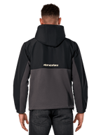 Alpinestars Juncture Hybrid jas, achteraanzicht, zwart en gunmetal, casual sportswear anorak met een mix van materialen, ripstop bovenzijde en canvas fleece onderzijde, Alpinestars-logo op de rug, gedragen met een donkere broek