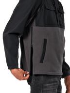 Alpinestars Juncture Hybrid jas in Black Gunmetal, detailweergave van de zijkant met focus op de zijrits en onderste paspelzak, ontwerp van gemengde materialen met grijs canvas fleece en zwarte ripstop overlays, casual op motorsport geïnspireerde streetwear