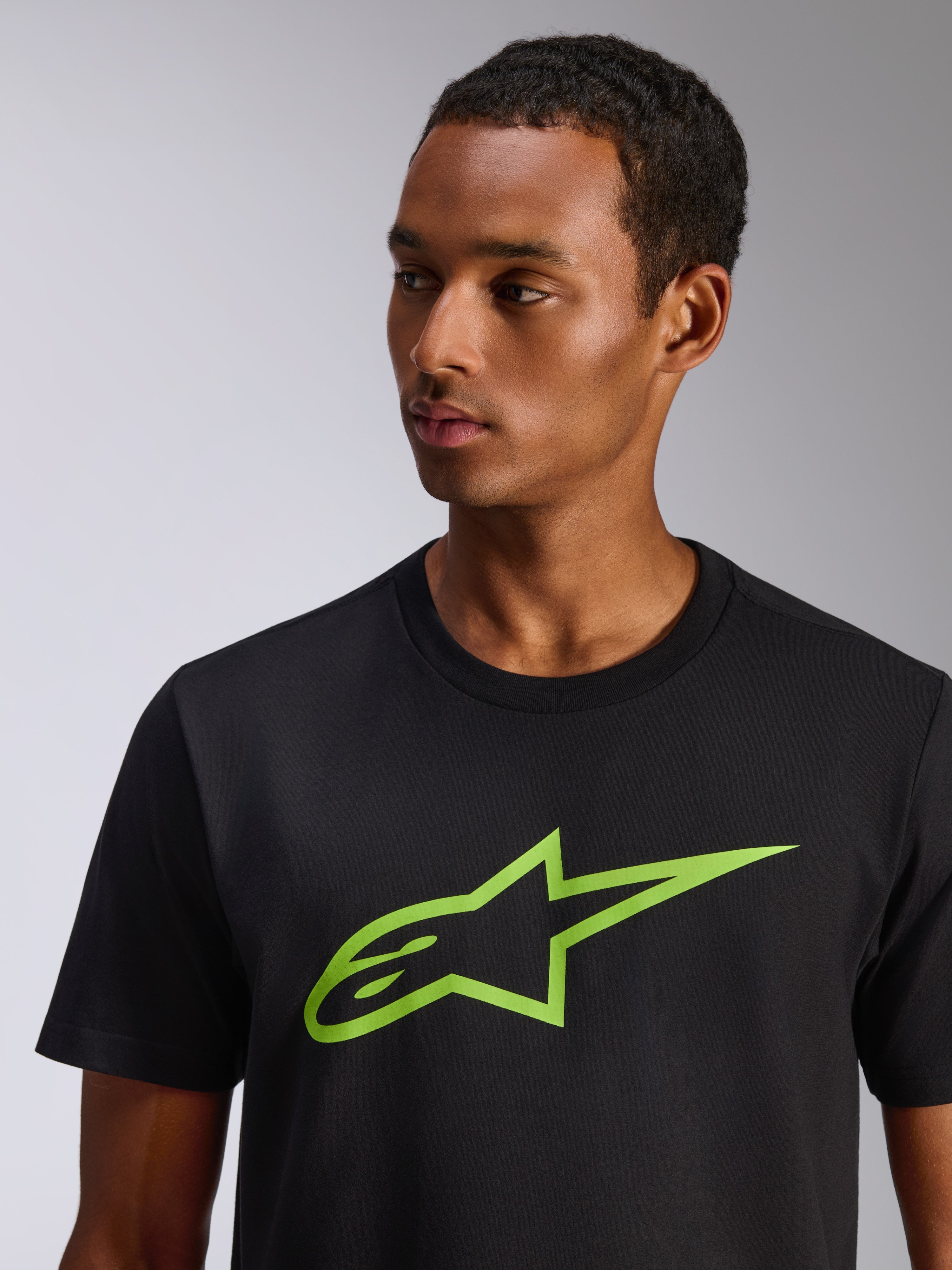 Alpinestars Ageless 2.0 CSF Tee, T-shirt met korte mouwen, zwart met limegroen Alpinestars sterlogo, gedragen door een mannelijk model, casual door motorsport geïnspireerde streetwear
