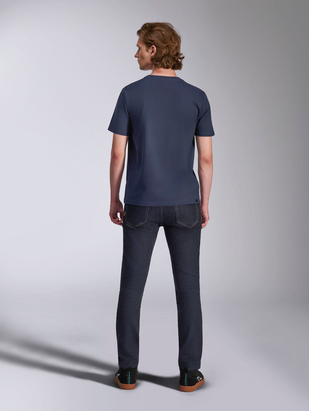 Alpinestars Ageless 2.0 CSF Tee, t-shirt à manches courtes, bleu marine, vue de dos, porté par un homme avec un jean en denim foncé et des baskets noires, streetwear décontracté d'inspiration sport automobile