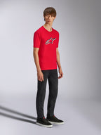 Alpinestars Ageless Shadow CSF Tee, rood T-shirt met korte mouwen, met een groot Ageless-logo op de borst, gedragen door een model met zwarte broek en sneakers, casual motorsport streetwear