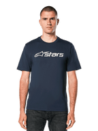 Alpinestars Blaze 2.0 CSF Tee, dunkelblaues kurzärmeliges T-Shirt mit weißer Astars-Logo-Grafik, getragen von einem Mann mit dunkler Jeans, lässige Motorsport-Lifestyle-Bekleidung