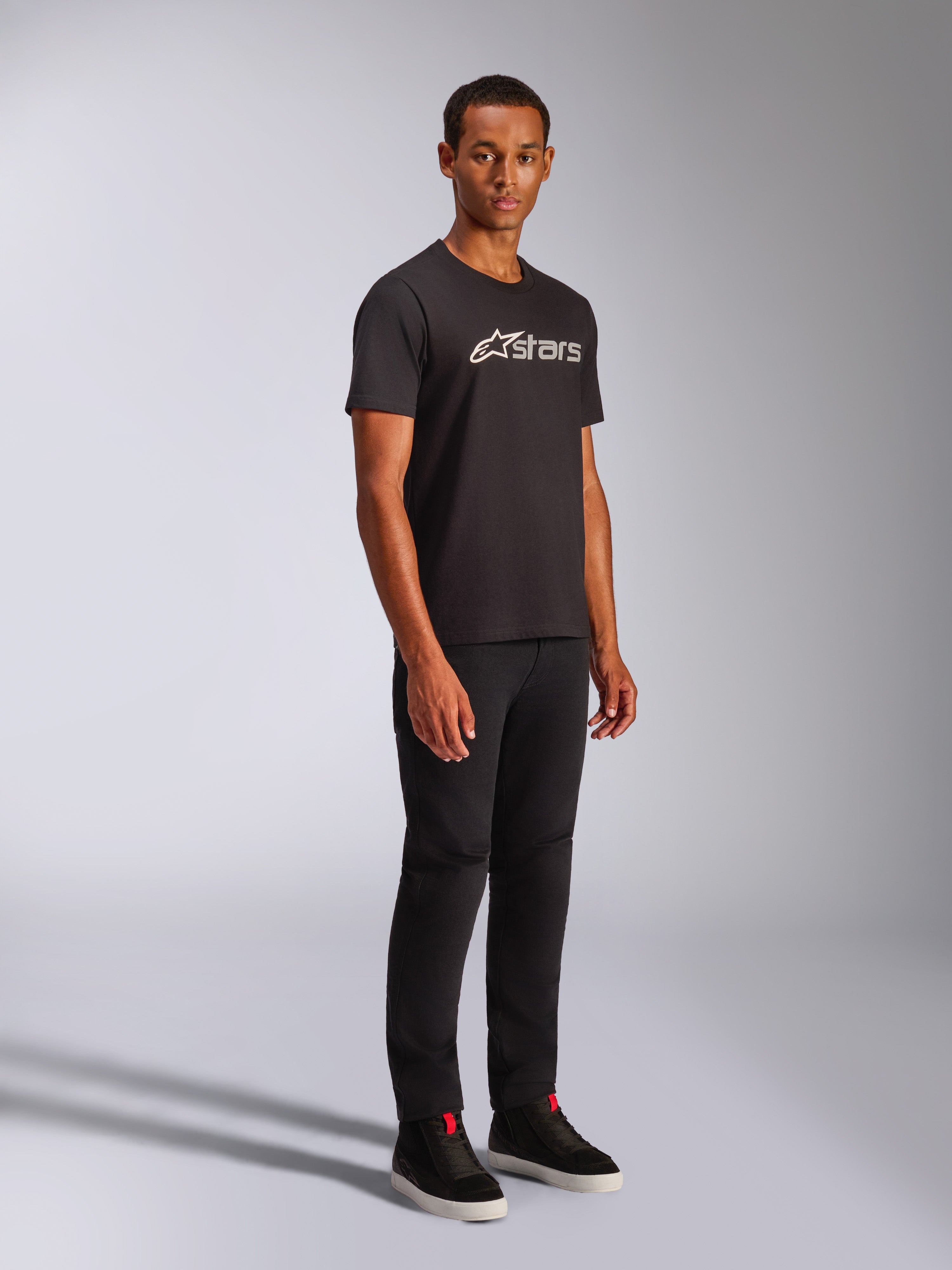 Alpinestars Blaze 2.0 CSF Tee, T-shirt met korte mouwen, zwart met wit en grijs grafisch logo, gedragen door mannelijk model met zwarte broek en hoge sneakers, casual motorsport streetwear
