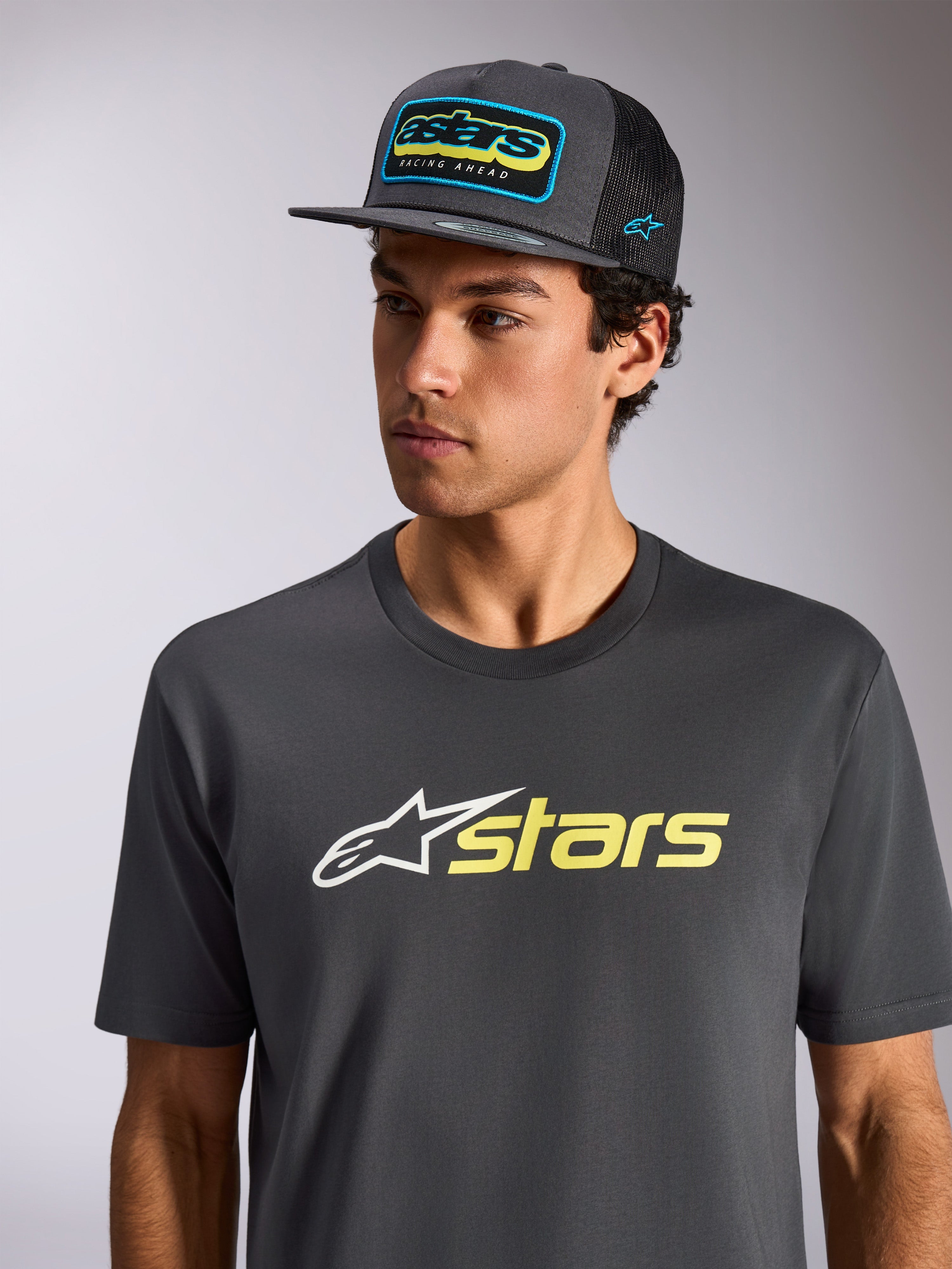 Alpinestars Blaze 2.0 CSF Tee, T-shirt met korte mouwen, antraciet met wit en hi-vis geel logo, gedragen met een bijpassende antracietkleurige pet met mesh-achterkant, casual motorsport-geïnspireerde sportkleding