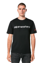 Alpinestars Linear Wordmark 2.0 CSF Tee, t-shirt met korte mouwen, zwart, grijs lineair woordmerk over de borst en rood Ageless-logo op de mouw, gedragen door een model met donkere jeans, casual op motorsport geïnspireerde streetwear