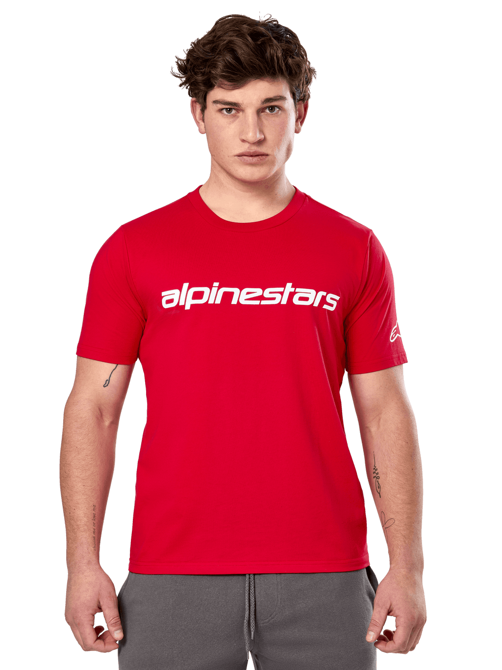 Alpinestars Linear Wordmark 2.0 CSF T-shirt, rood shirt met korte mouwen, wit lineair woordmerk op de borst en Ageless-logo op de mouw, mannelijk model met grijze joggingbroek, casual motorsport-geïnspireerde streetwear
