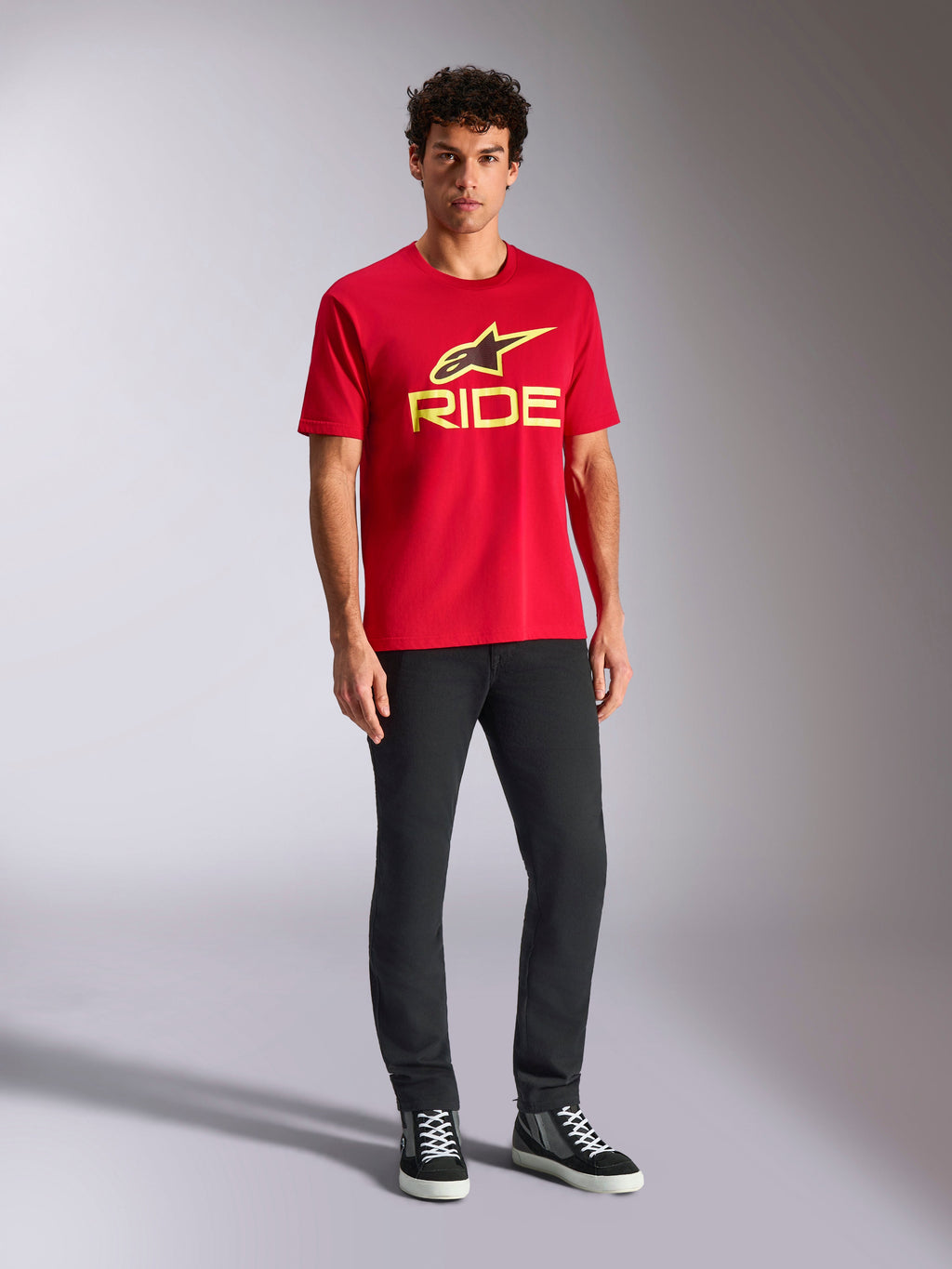 Alpinestars Ride 4.0 CSF Tee, T-shirt met korte mouwen, rood met Hi-Vis geel Alpinestars ster- en Ride-logo, gedragen door model met zwarte broek en sneakers, casual motorsport sportkleding