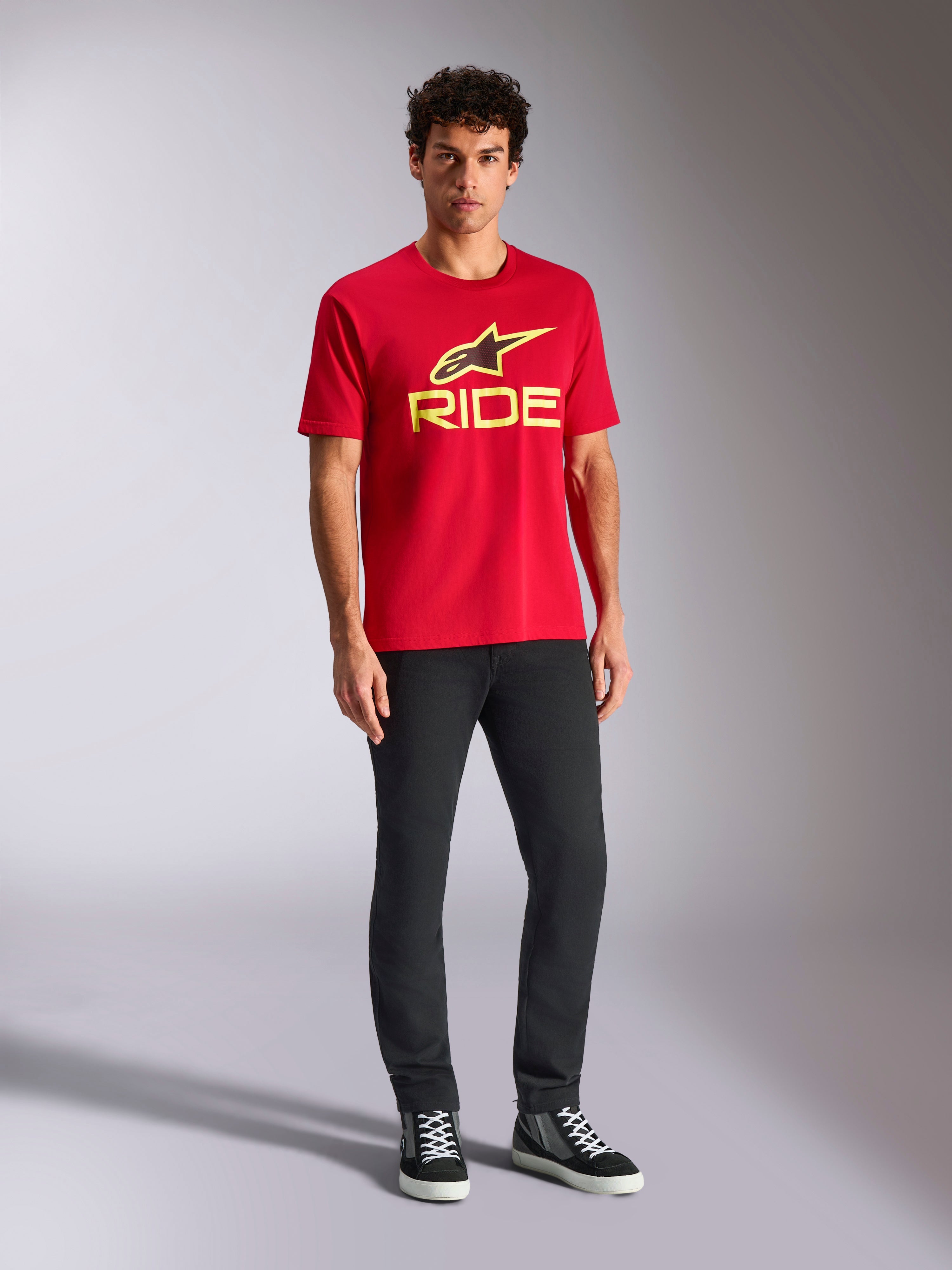 Alpinestars Ride 4.0 CSF Tee, T-shirt met korte mouwen, rood met Hi-Vis geel Alpinestars ster- en Ride-logo, gedragen door model met zwarte broek en sneakers, casual motorsport sportkleding