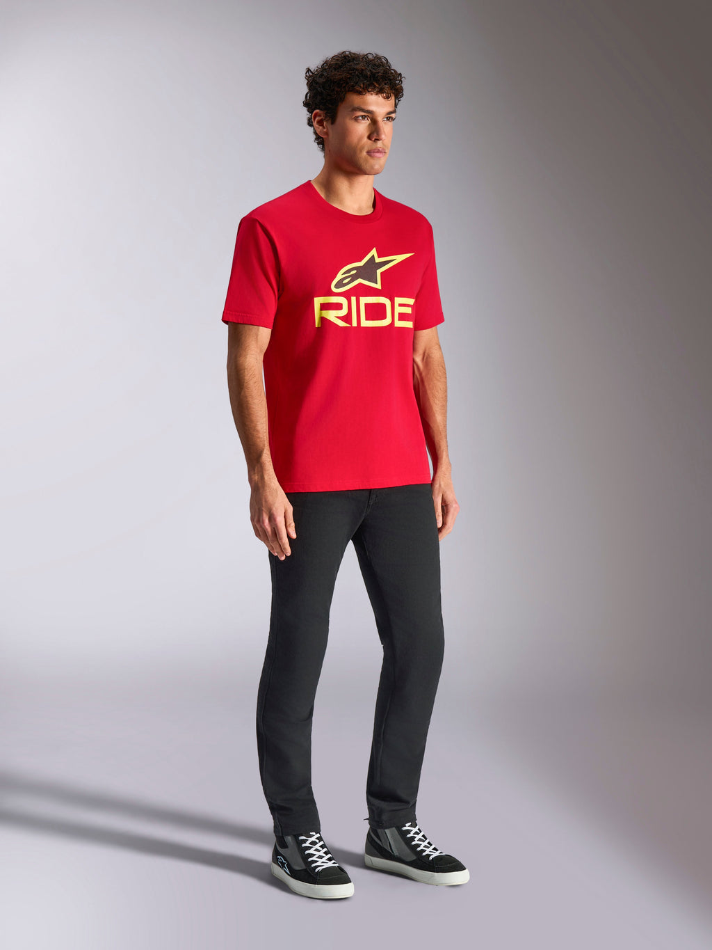 Alpinestars Ride 4.0 CSF Tee, T-shirt met korte mouwen, rood, geel en zwart logo op de voorzijde, gedragen met een zwarte broek en sneakers, casual motorsport streetwear