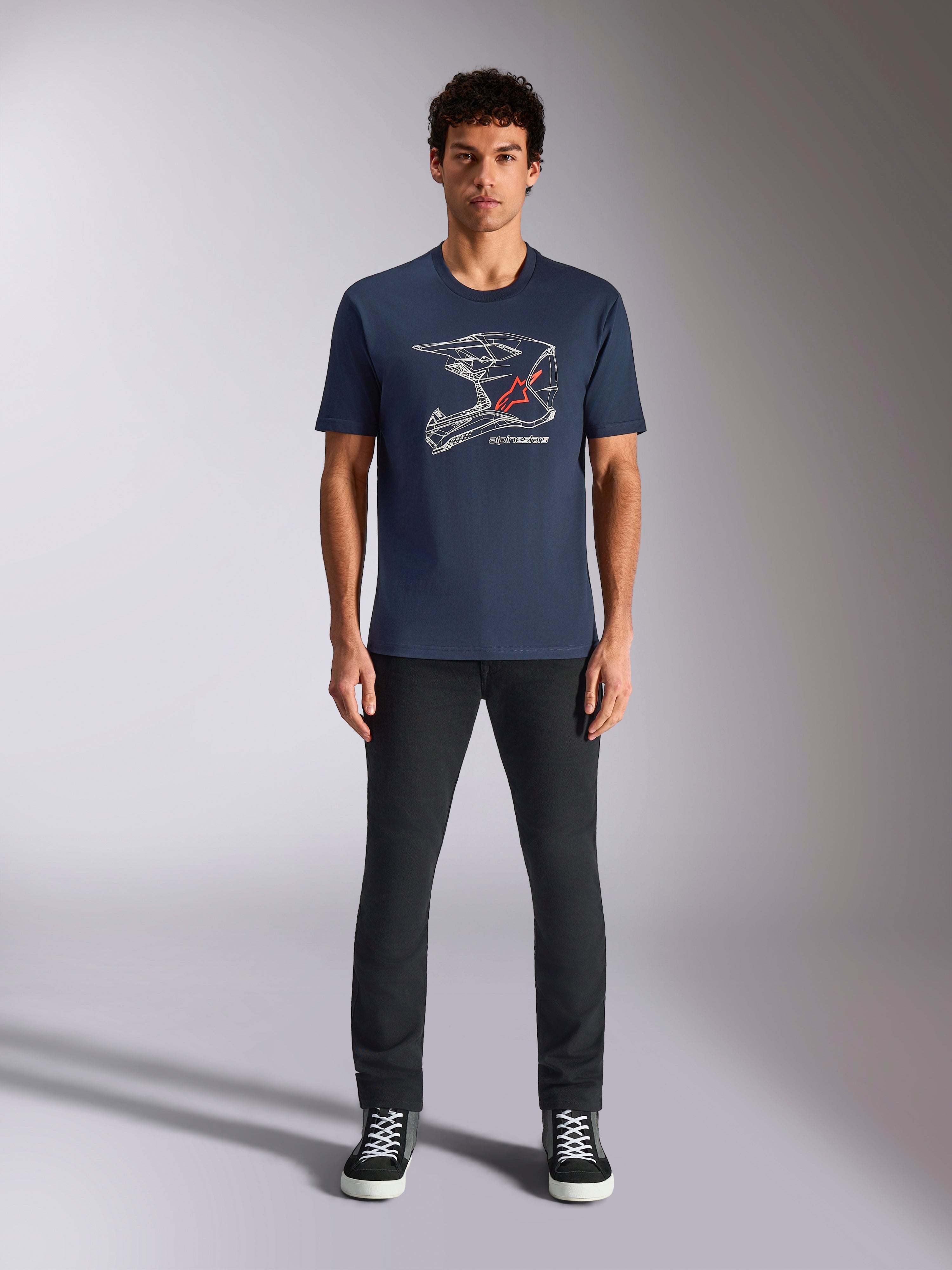 Alpinestars MX Helmet CSF Tee, T-shirt met korte mouwen, marineblauw, met witte motorcrosshelm-graphic en rood sterlogo, gedragen door model met zwarte broek en sneakers, casual motorsport-geïnspireerde streetwear
