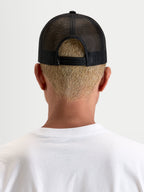 Alpinestars Heritage Patch Trucker pet, casual mesh back hat, zwart, achteraanzicht met verstelbare snapbacksluiting en poly mesh constructie gedragen door een model