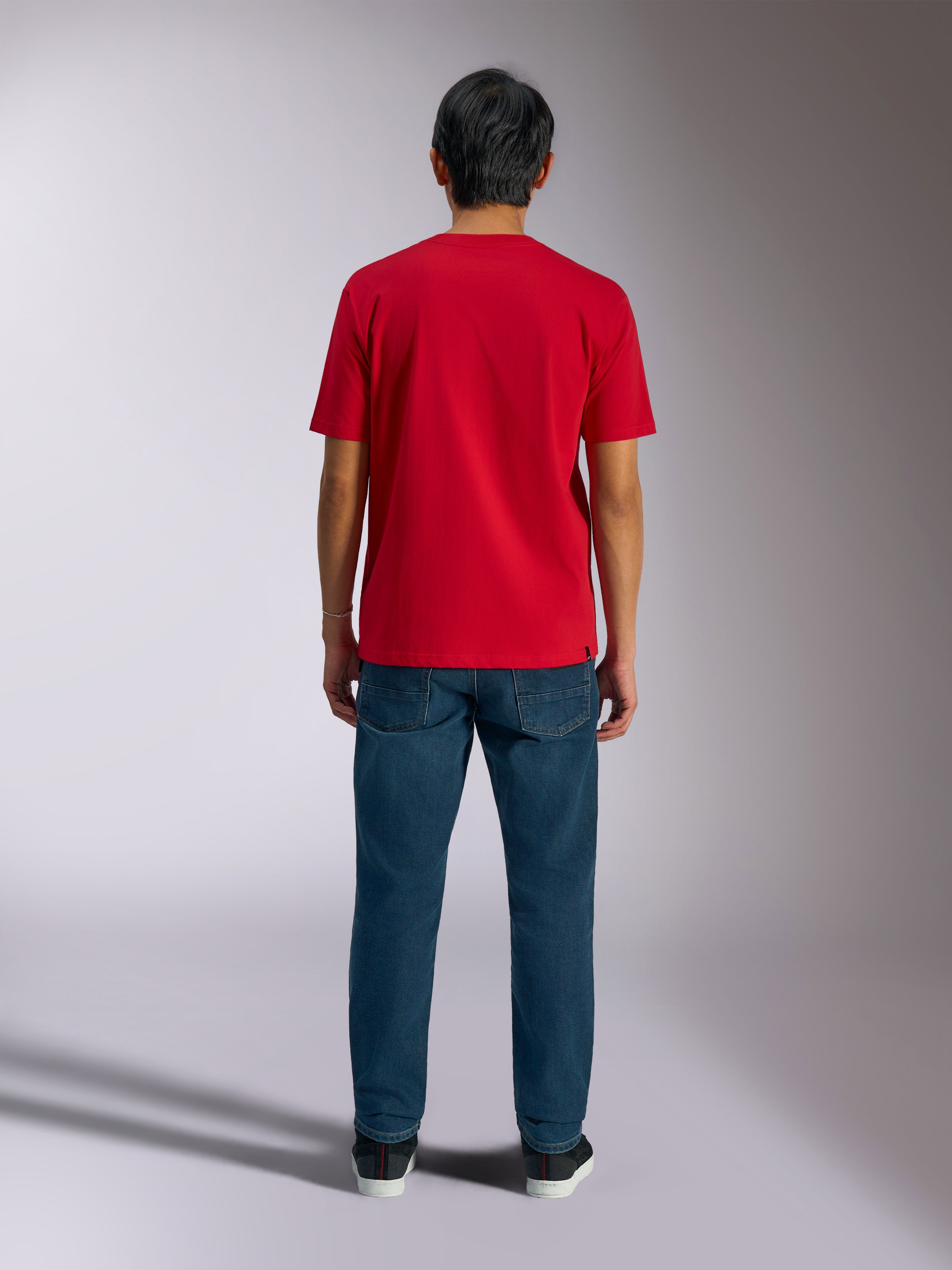 Alpinestars Ageless Shadow CSF Tee, achteraanzicht van rood T-shirt met korte mouwen, gedragen met donkerblauwe denim jeans en zwarte sneakers, casual motorsport streetwear