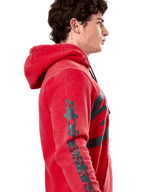 Alpinestars Unbound Hoodie, rode pullover fleece hoodie, zijprofiel met donkergrijs Alpinestars-woordmerk op de mouw, garment-dyed afwerking met een capuchon met trekkoord, casual motorsport streetwear