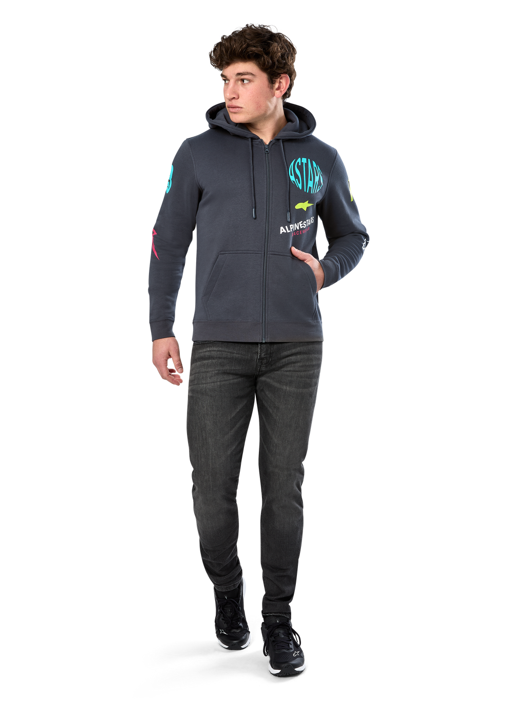 Alpinestars Variegate Hoodie, fleece hoodie met ritssluiting, Gunmetal grijs, gedragen door een model met zwarte jeans en sneakers, voorzien van teal 'ASTARS' branding en kleurrijke logo-art op de mouwen en borst, casual op de motorsport geïnspireerde streetwear