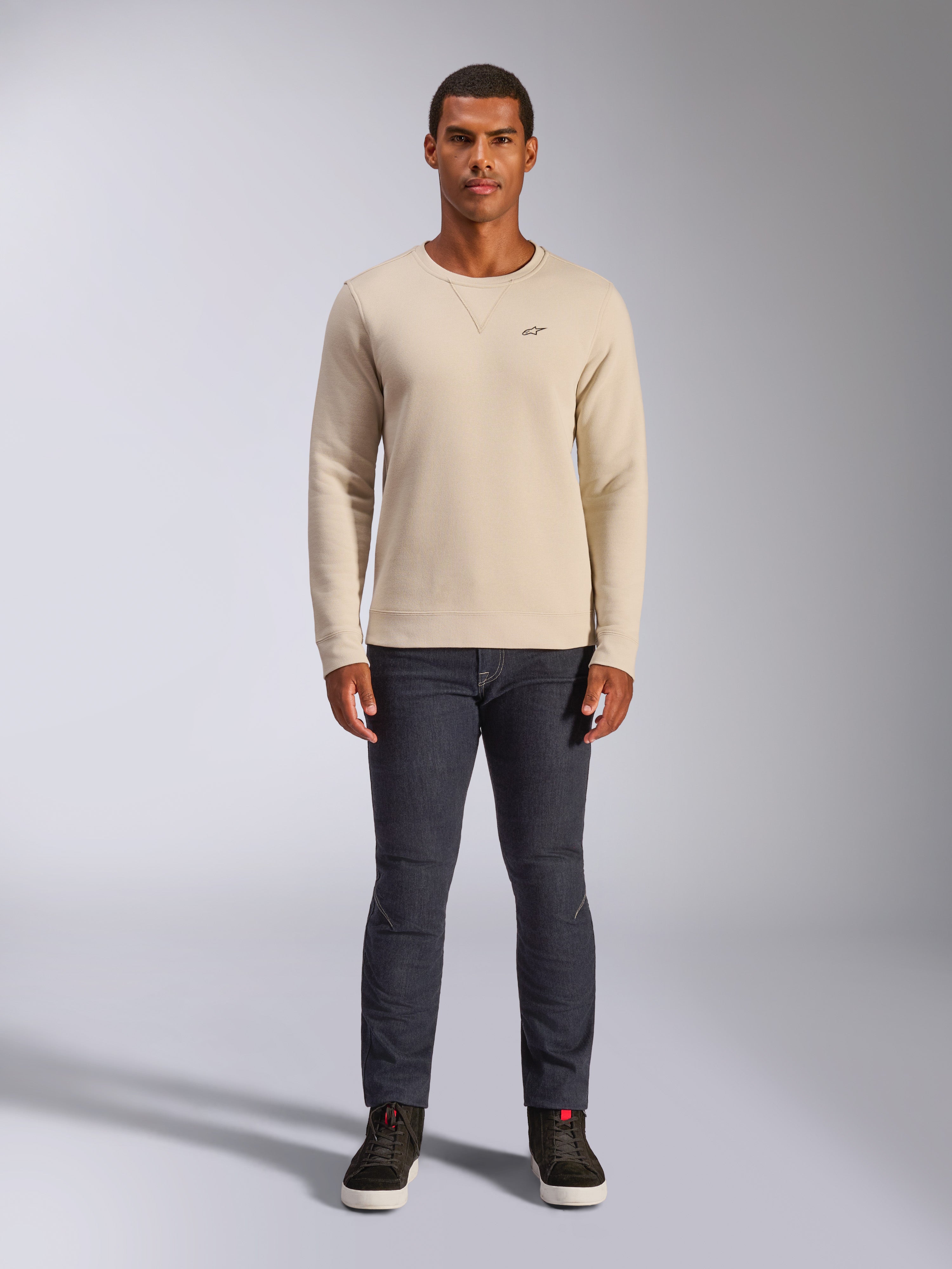 Alpinestars Positive Crew, Off White sweatshirt met ronde hals, klein zwart logo op de borst, geribbelde manchetten en zoom, driehoekig stiksel bij de hals, casual motorsport streetwear gedragen met een donkere jeans