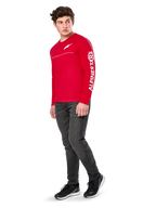 Alpinestars Committed CSF Tee, T-shirt met lange mouwen, rood, met wit Astars-logo op de borst en Alpinestars-branding op de mouw, gedragen door een model met donkere jeans en zwarte sneakers, casual motorsport streetwear