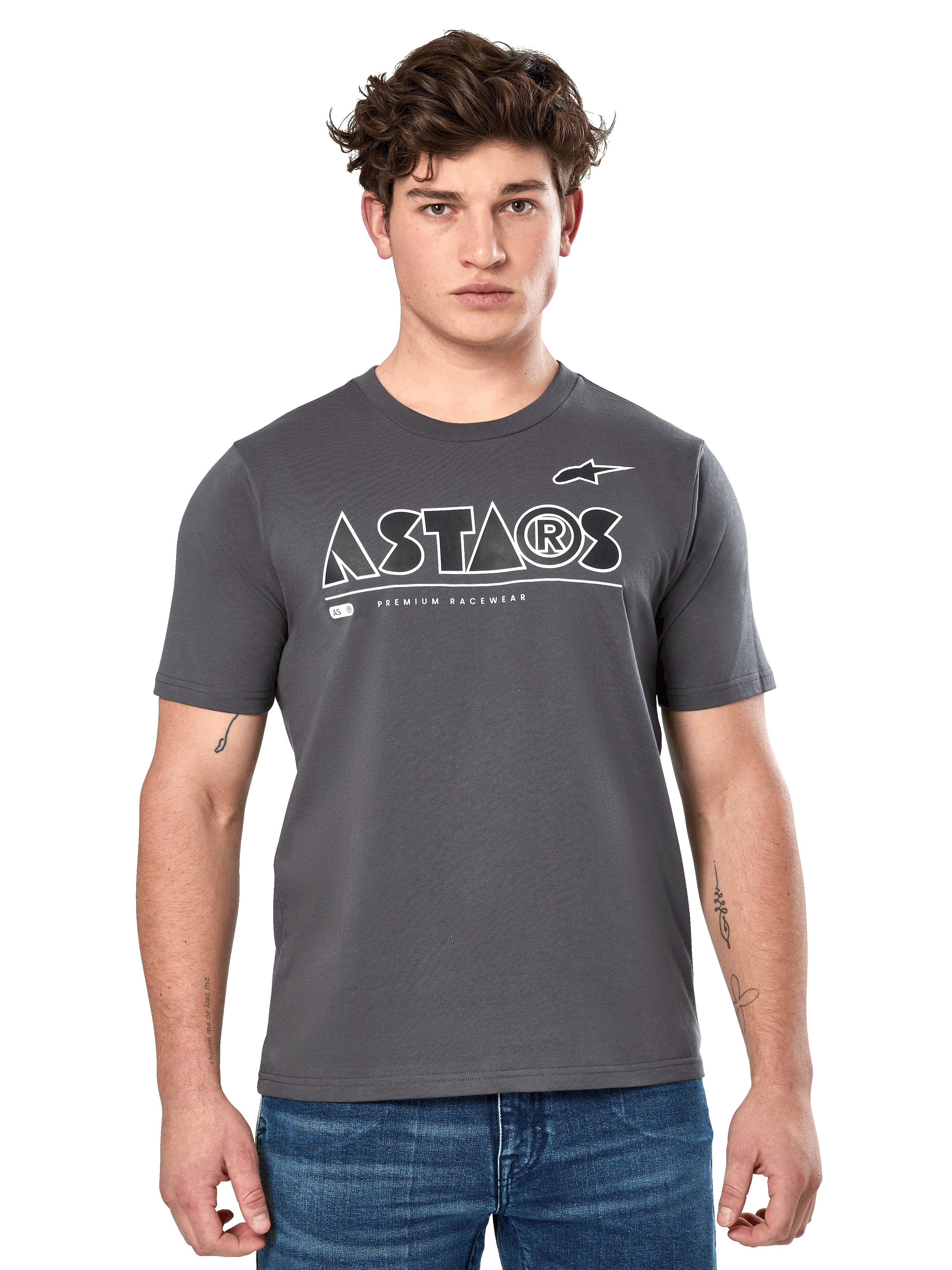 Alpinestars Cereal CSF Tee, antracietgrijs T-shirt met korte mouwen, gedragen door een mannelijk model met een blauwe jeans, wit geometrisch ASTARS-logo en 'Premium Racewear'-tekst, casual motorsport-geïnspireerde lifestyle kleding