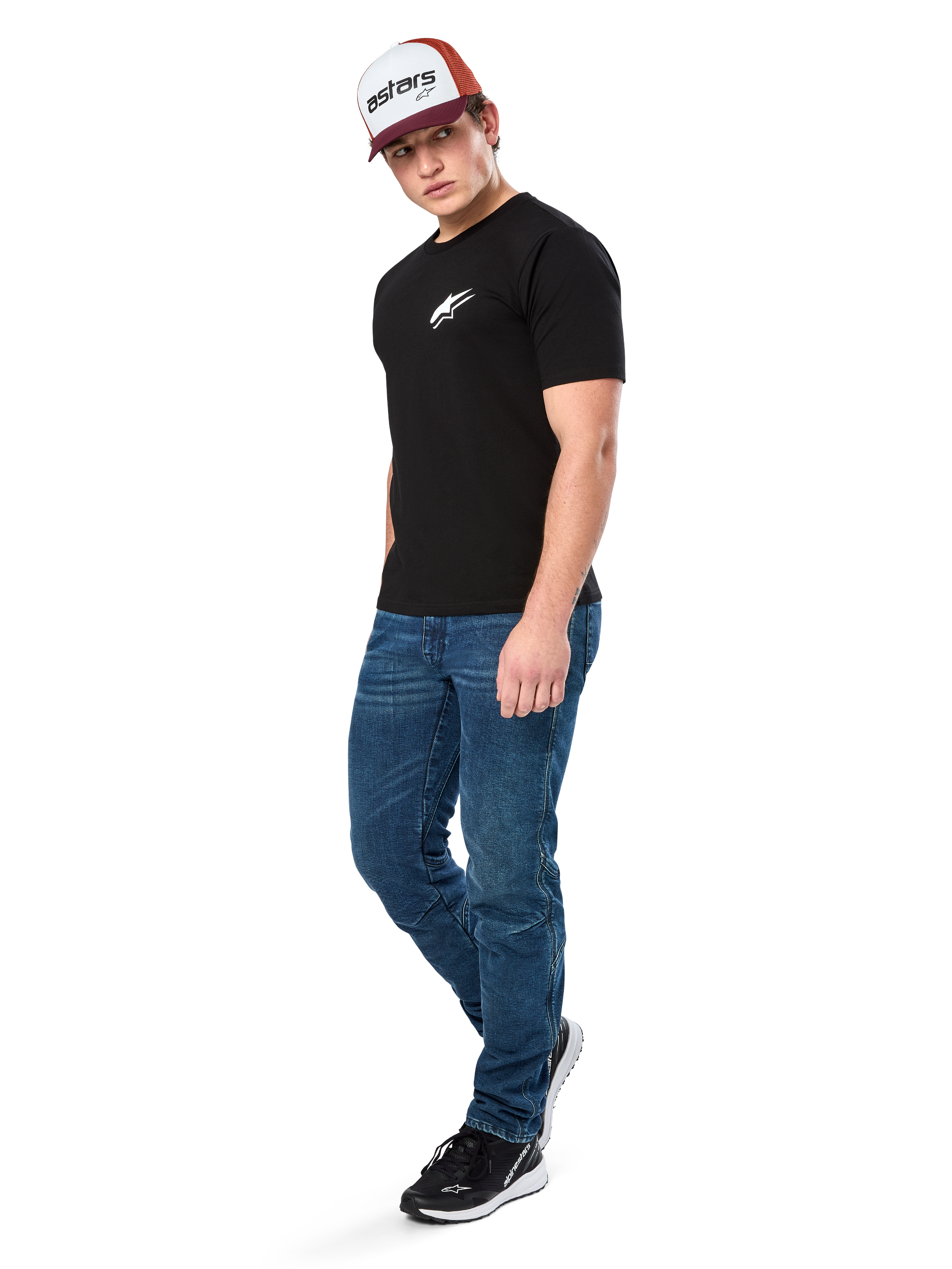 Alpinestars Formulate Csf Tee, T-shirt met korte mouwen, zwart met wit Astars-logo op de borst, gedragen door een model met blauwe jeans, een bordeauxrode en witte pet en zwarte sneakers, casual motorsport-geïnspireerde streetwear